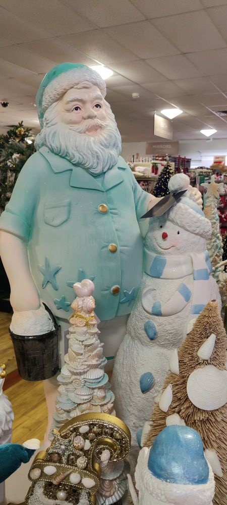 A Home Goods statue of Santa wearing a light blue Polo with starfish on it while wrapping his arm around a snowman who is somehow not melting despite the implication that it is hot and sunny.