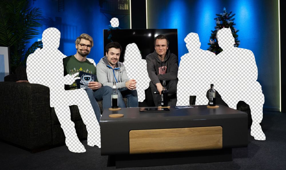 Personen sitzen auf der Couch, vor ihnen steht ein Sofa-Tisch und im Hintergrund ist ein TV und ein Weihnachtsbuam/Weihnachtsdeko zu erkennen. Ein paar der Personen sind ausgeschnitten und man erkennt nur ihre Umrisse.