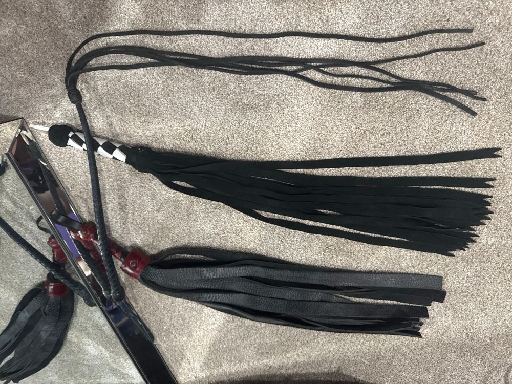 A photo of three different hand made impact-play toys. The photo is upside down for some reason but as pictured:
The bottom is a flogger made from bison hide with wide falls. The middle one is also a flogger, but you can see the notches in the end to make those ends skinnier to add a bit of sting. The top item is a five-tail cat with thin leather falls for a much stingy-er experience. 