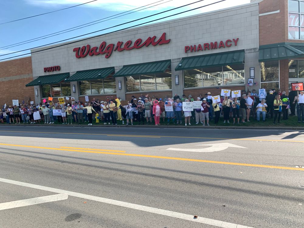 Crowd of people with signs standing outside Walgreens.