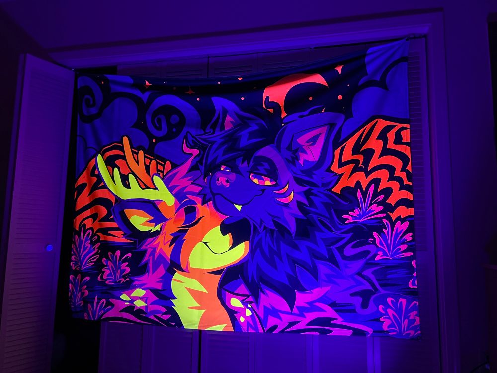 A tapestry of a deer and a hyena in the desert. The tapestry is draped over a closet and is shown using a black light.