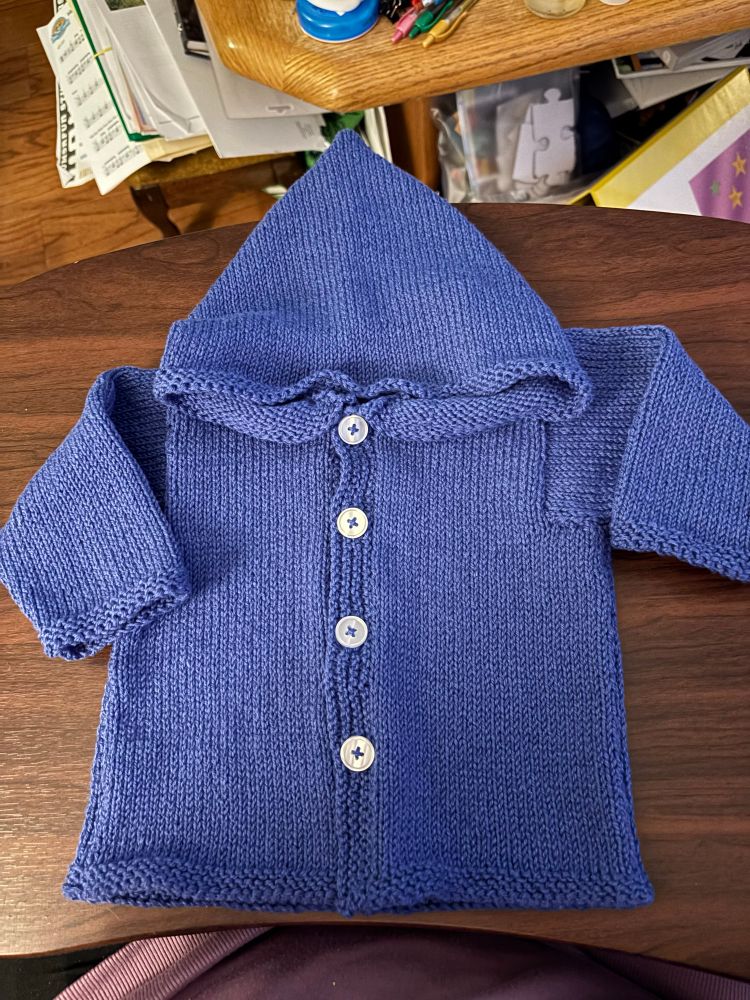 A blue knitted baby’s hooded sweater with 4 white buttons