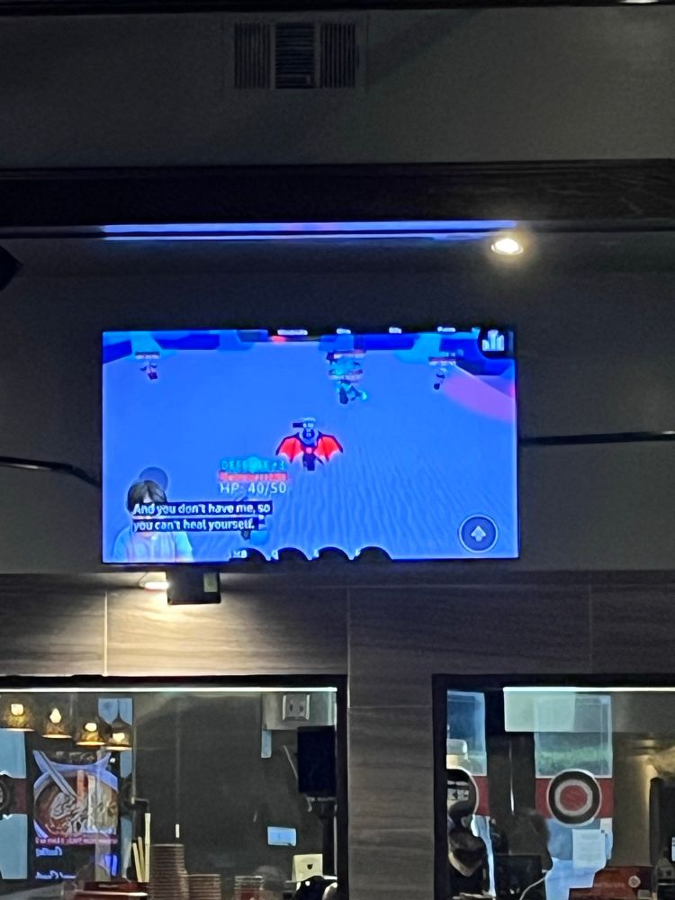 Revolving sushi restaurant showing Roblox videos with subtitles on one of their TVs