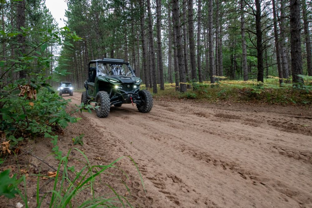 Off-road vehicles drive down a dirt road.