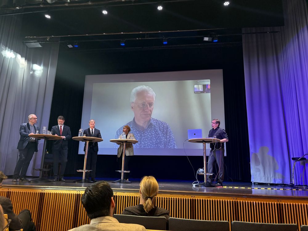 Allan Manning on a big screen behind the panel at the conference Modern Labor Markets in Stockholm