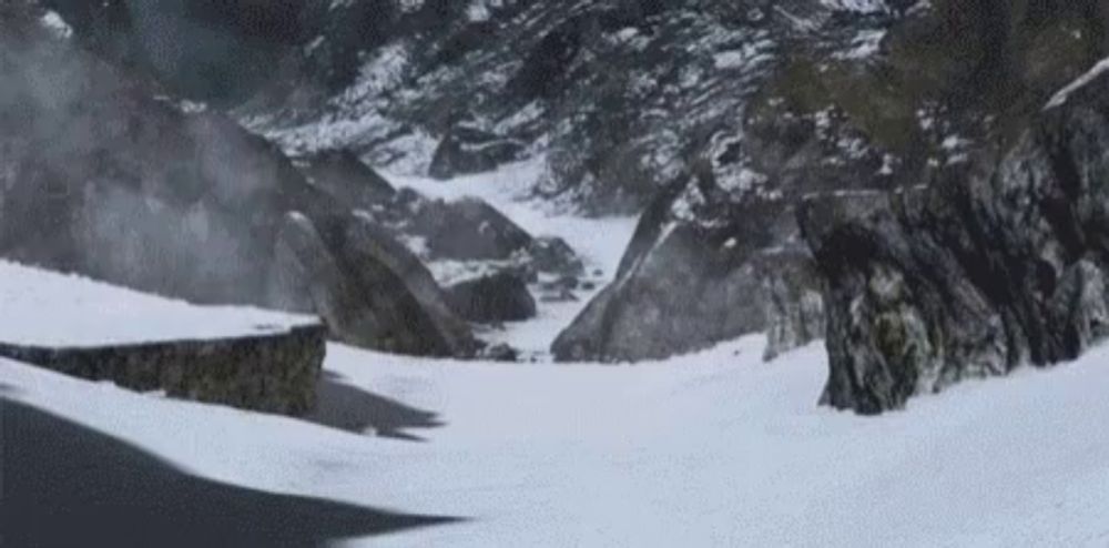 a snowy mountain landscape with a road going through it .