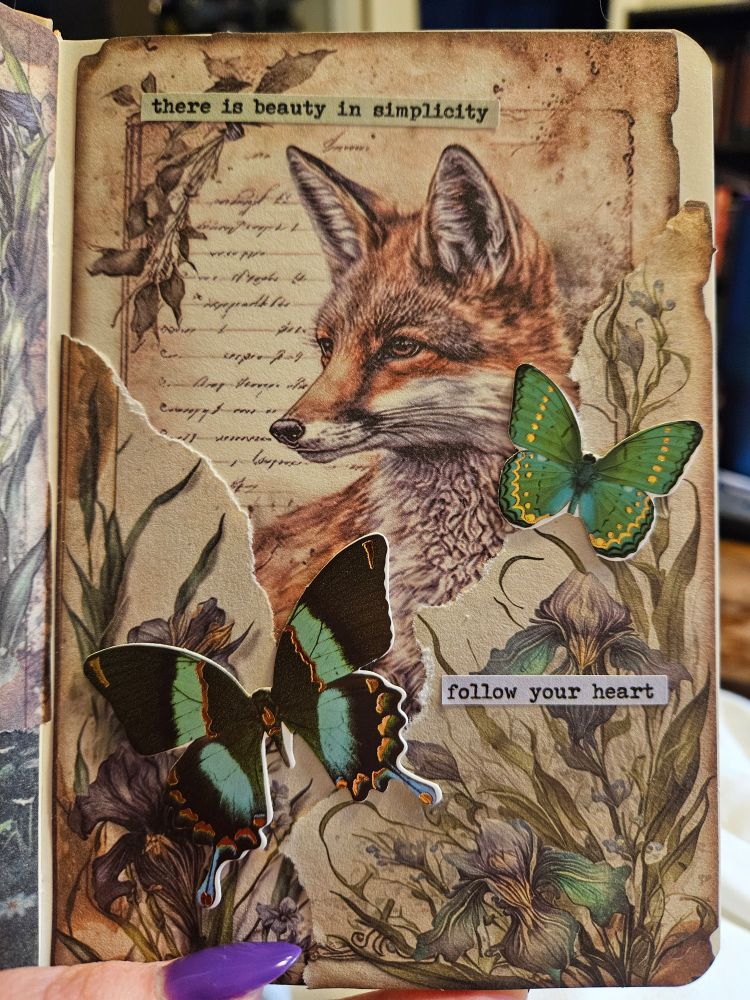 A sepia toned scrapbook page featuring Iris flowers in the bottom two corners and a Fox behind them. Two green butterflies sit on either side of the Fox, taped to the pages to give a 3D effect. The words "there is beauty in simplicity, follow your heart" are written on the page.