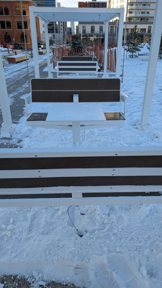 A picture taken from the end of one of the units and you can see that there is dark wood on the back and seat of each swing. The table in the middle, and all of the metal surrounding is white.