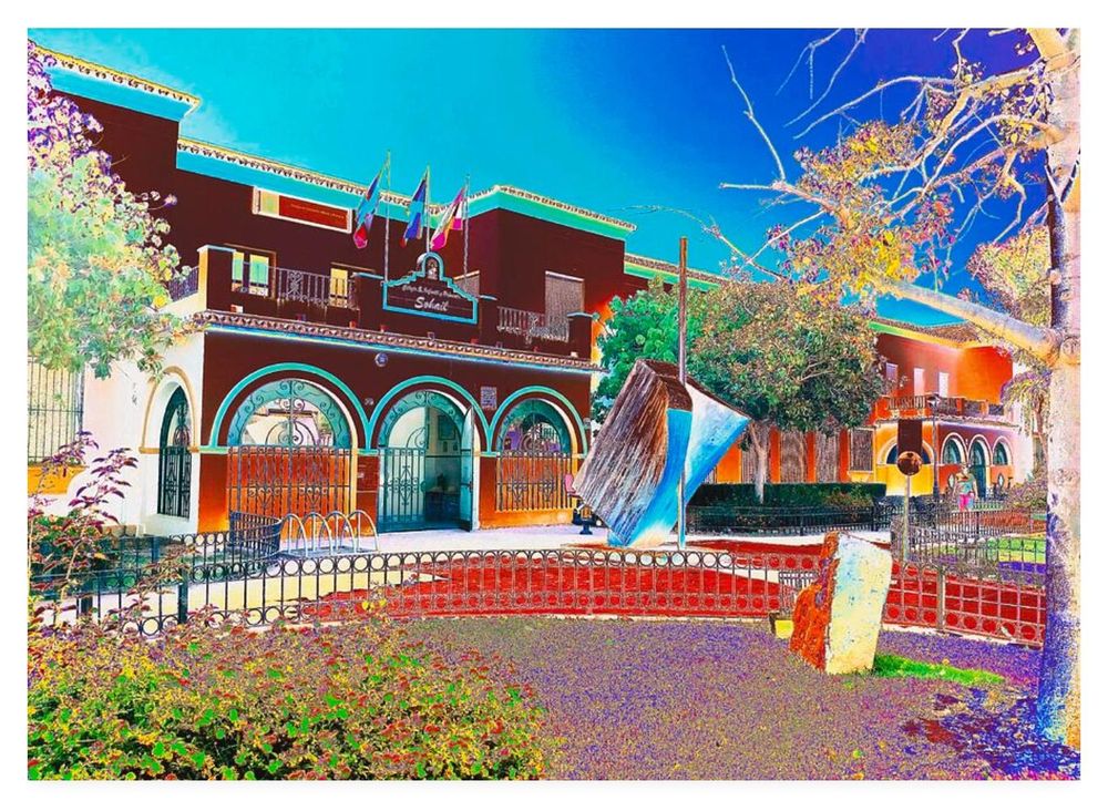 Colour adjusted (overly colourful) photograph showing the front of Sohail School in southern Spain with an open book sculpture out front.