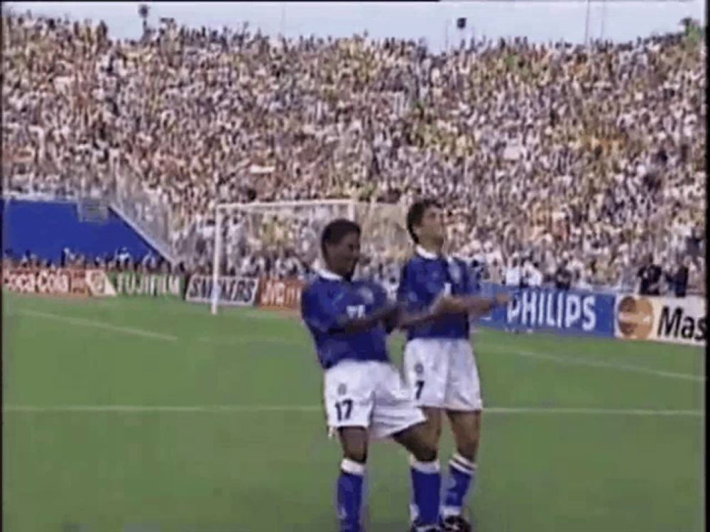 two soccer players are dancing on the field during a game .