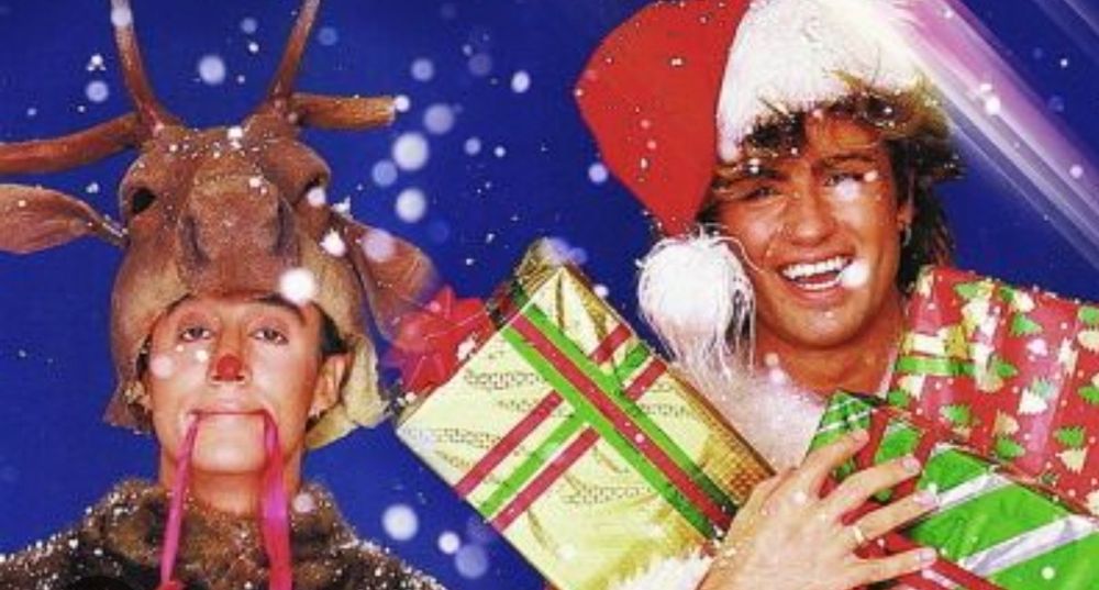 The photo from the cover of Last Christmas: Andrew is on the left of the photo, dressed as a reindeer. George is on the right, dressed as Santa and juggling presents. Snow is falling.