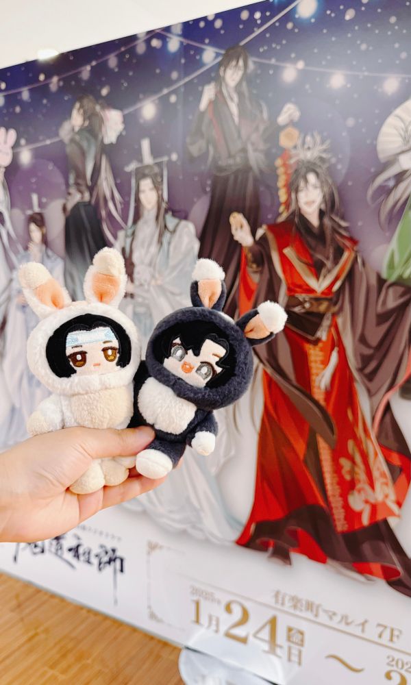 Photo of Wangxian bunny nuis, standing outside the MDZS JP audio drama 5th anniversary banner. 