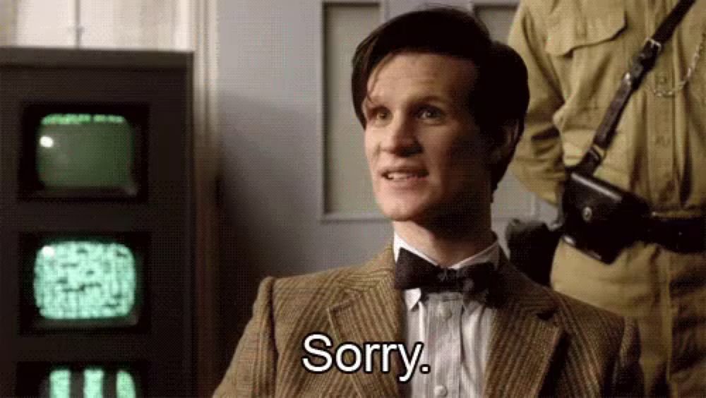 a man in a suit and bow tie is sitting in front of a television and saying `` sorry '' .