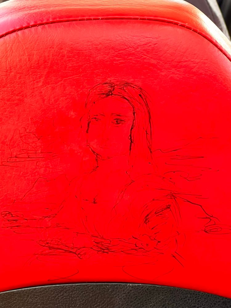 Someone has drawn a version of the Mona Lisa on the back of a bus seat with a biro
