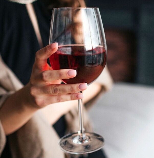 Glas rode wijn in de hand van een persoon.