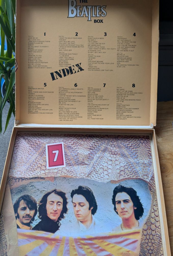 An open box with track listings for 8 vinyl records by The Beatles and one album with a picture of the band on the cover 