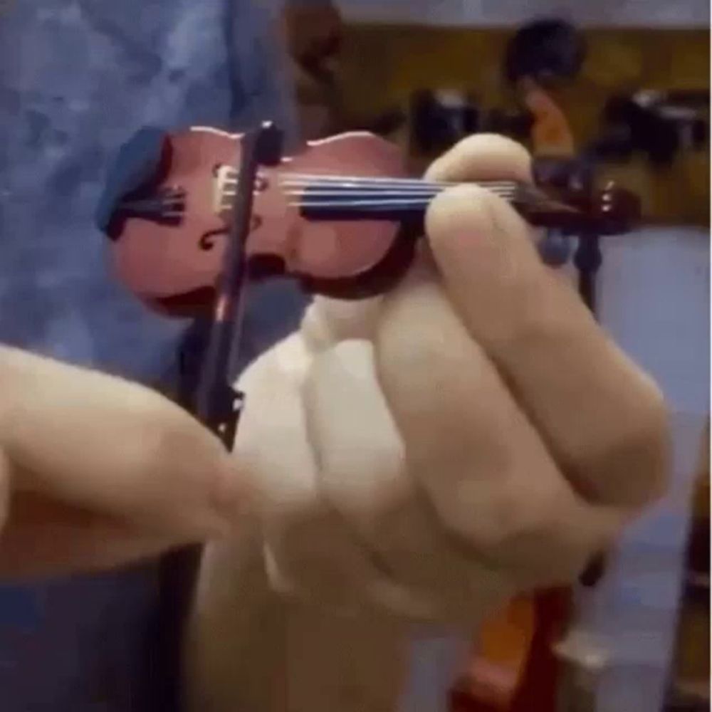 a person is holding a miniature violin in their hand .