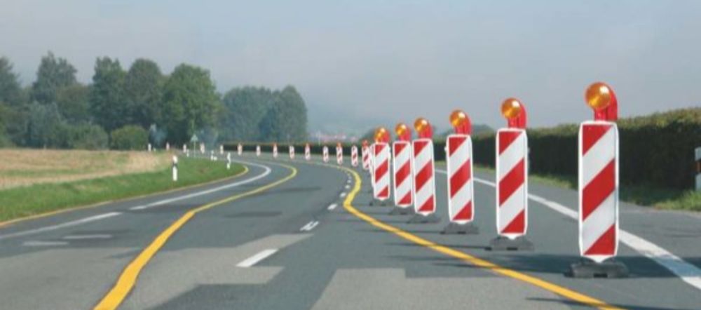 Bild einer Fahrbahnverschwenkung mit gelben Fahrbahnmarkierungen und Absicherung durch Leitbaken mit Signalleuchte 