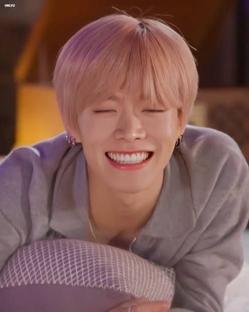 Nct yuta smiling to show off all his teeth with his eyes shut as he hugs a pillow.