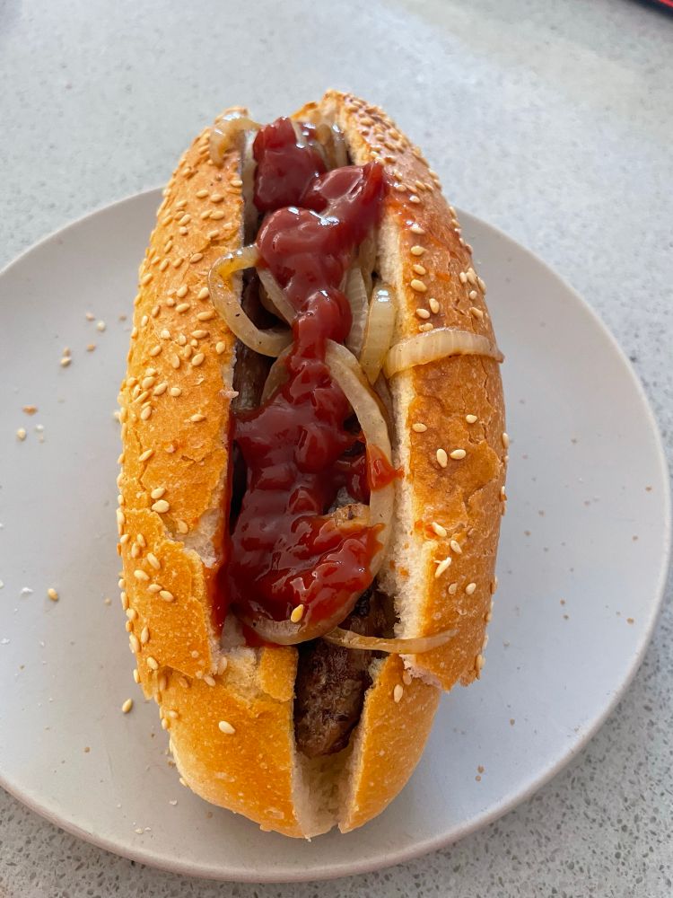 Home cooked democracy sausage in seeded bread rolls with sauce and onions