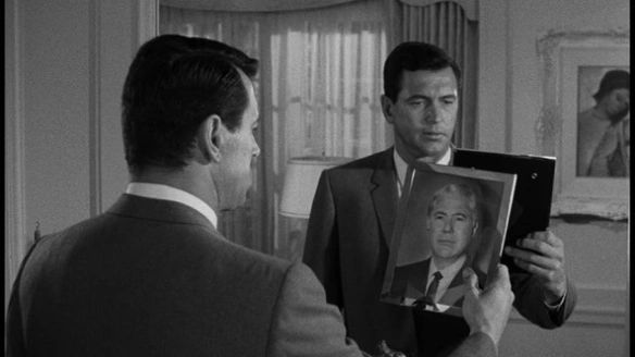 The protagonist (played by Rock Hudson) gazes at a picture of his former face (surgically scrubbed from existence and socially obliterated with a faked death) while also being caught in a mirror reflecting the new. He looks tremendously sad. 