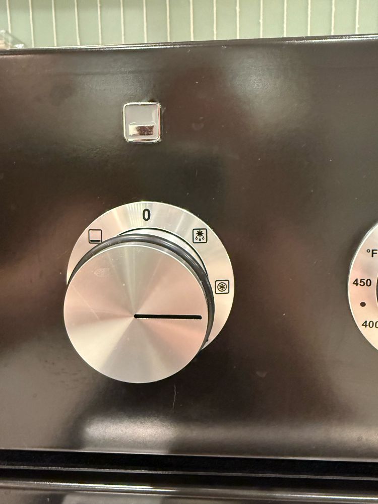 A round stove dial turned to convection mode. 