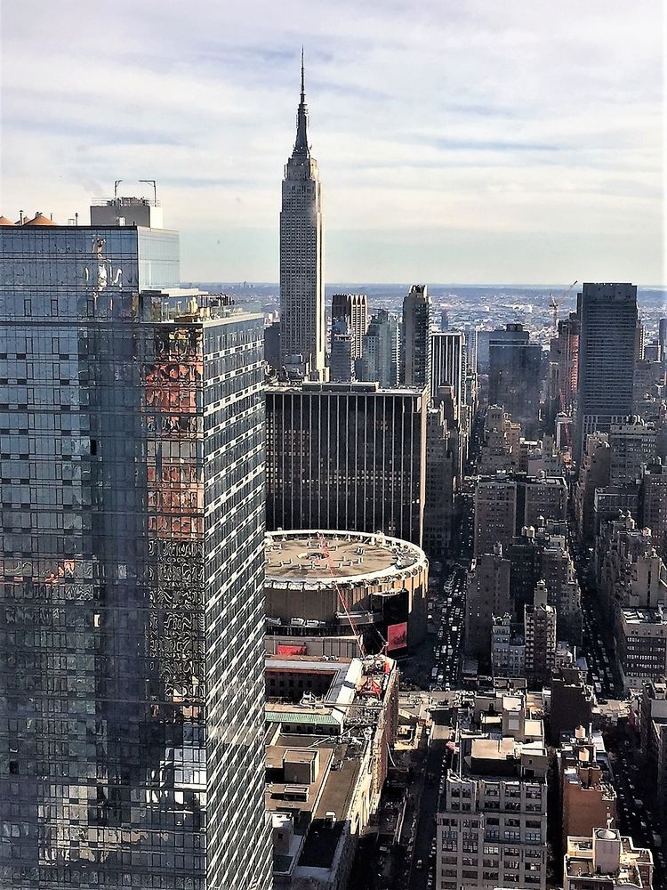 Der Blick auf eine Großstadt mit Hochhäusern, kleineren Häusern, Straßen und Autos fotografiert aus einem Fenster in einem hohen Stockwerk eines Hochhauses.