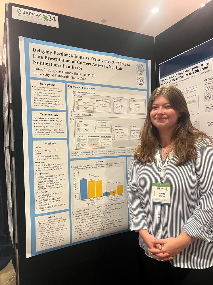 A woman standing next to a research poster titled, “Delaying Feedback Impairs Error Correction Due to Late Presentation of Correct Answers, Not Late Notification of an Error”