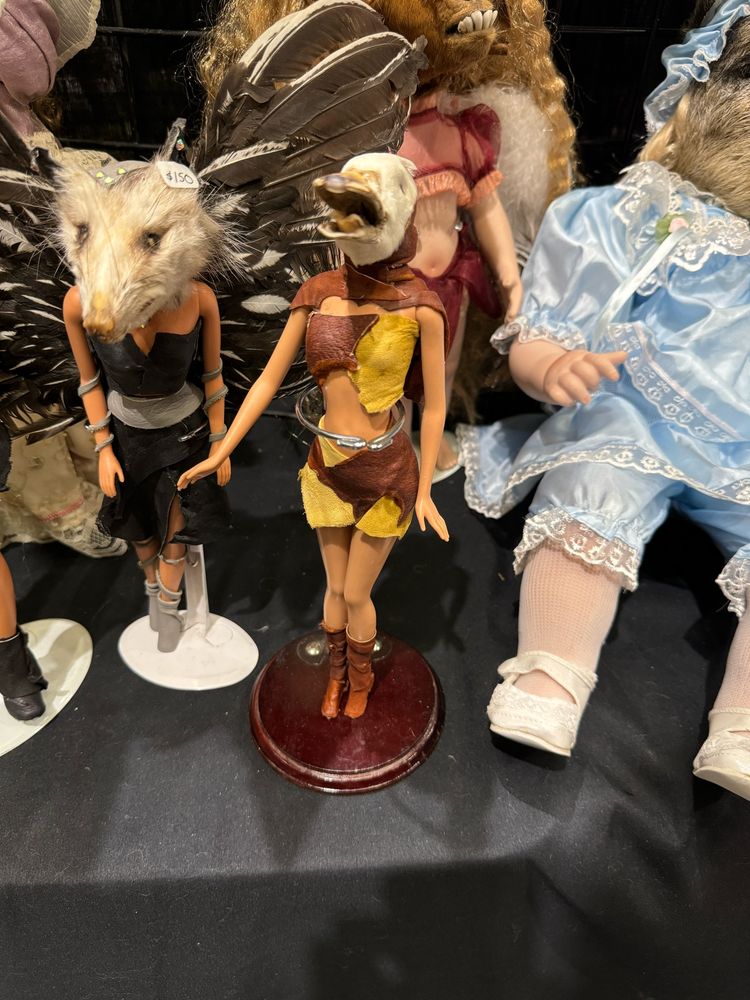 A doll with a femme (Barbie, perhaps?) body in a patchwork leather top and skirt