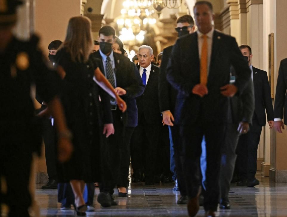 Benjamin Netanyahu, flanked by aides, walking down a corridor