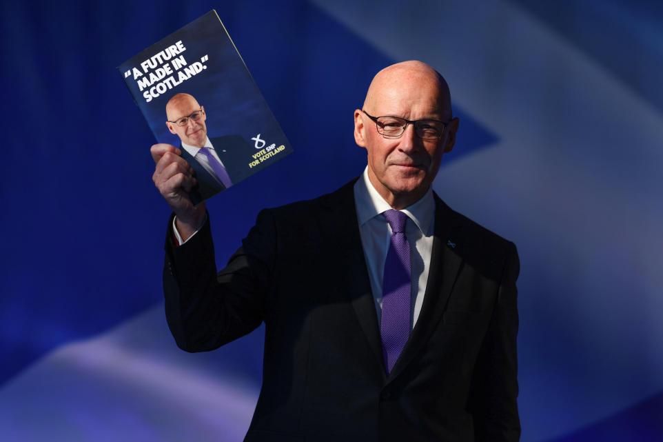 John Swinney holding up a copy of the SNP's 2024 General Election manifesto, 'A Future Made in Scotland'