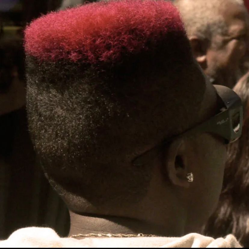 Back of person head turned to the side with Black sunglasses and red flag top