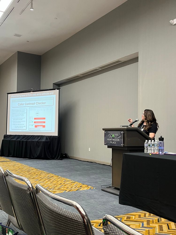 Priscila presenting at a podium on using a color contrast checking