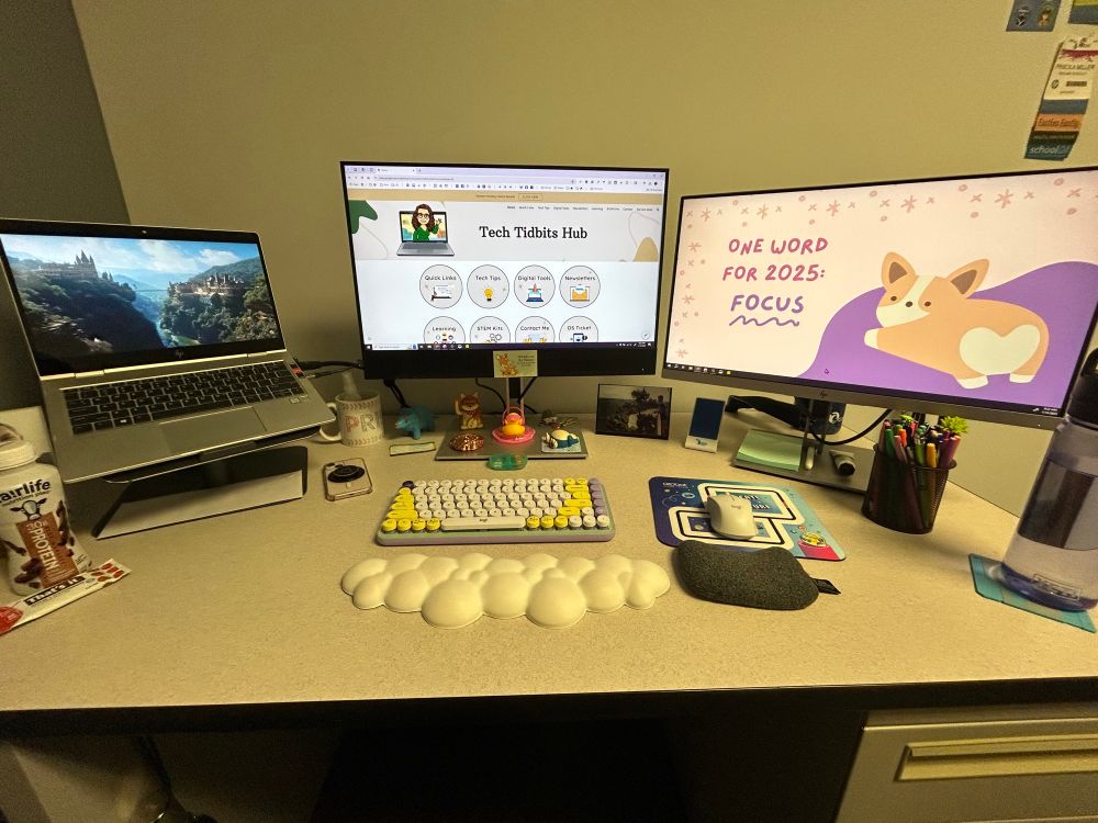 Work setup with laptop and 2 monitors. Left screen has fantasy image, middle screen has Tech Tidbits Hub website, right screen has background with One Word for 2025: Focus & a corgi cartoon