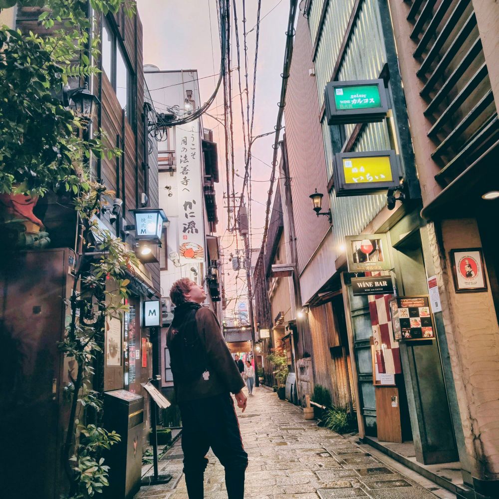 A tourist immersing themselves into the rainy alleyways of Namba Ōsaka.