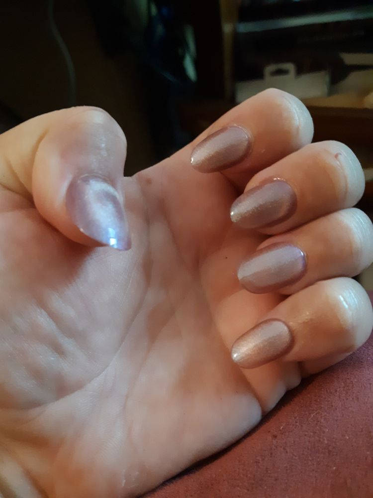 Photo of a hand with long pearlescent pink press on nails