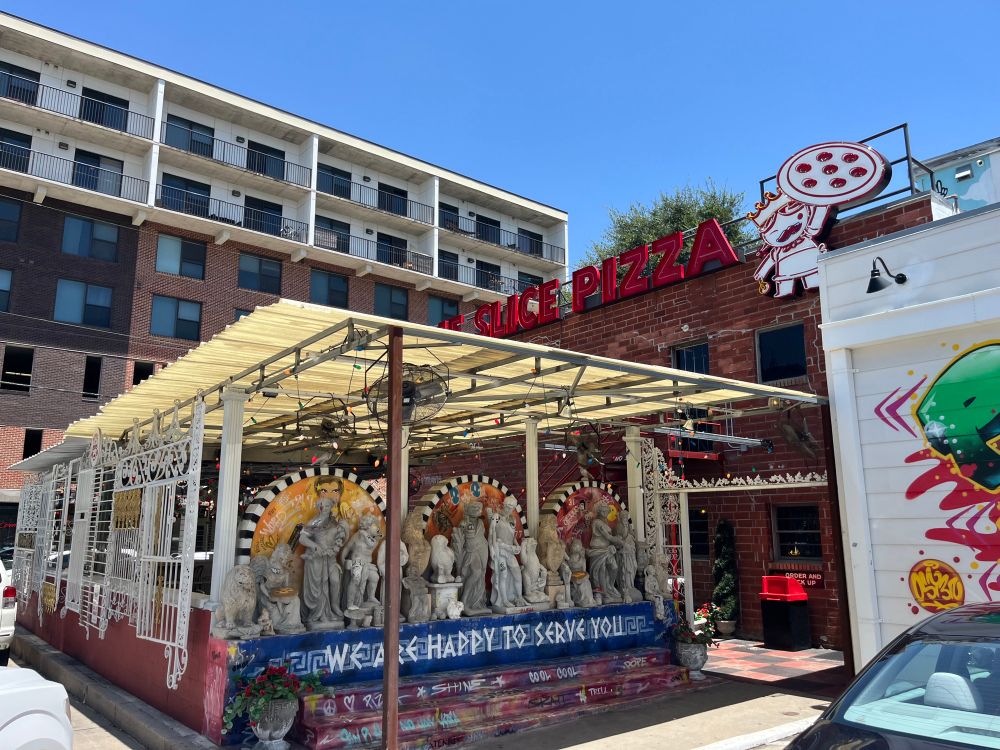 Exterior of Home Slice Pizza, with statuary-lined patio. 
