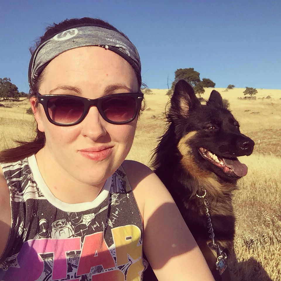 Loki and Steph sitting on a hillside after a run