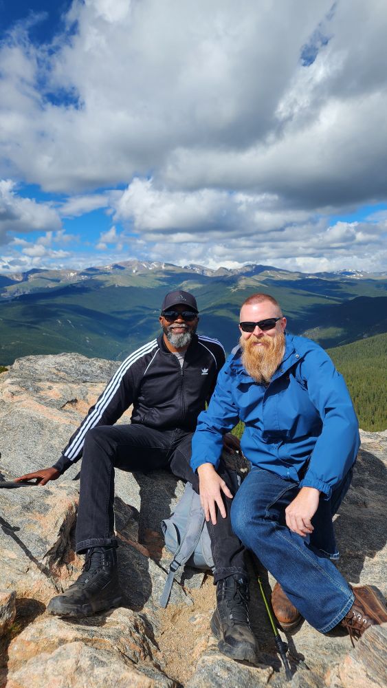 My partner and I sitting on top of the summit of Chief Mountain, with the Rocky Mountains (and Mount BlueSky) in the background. 