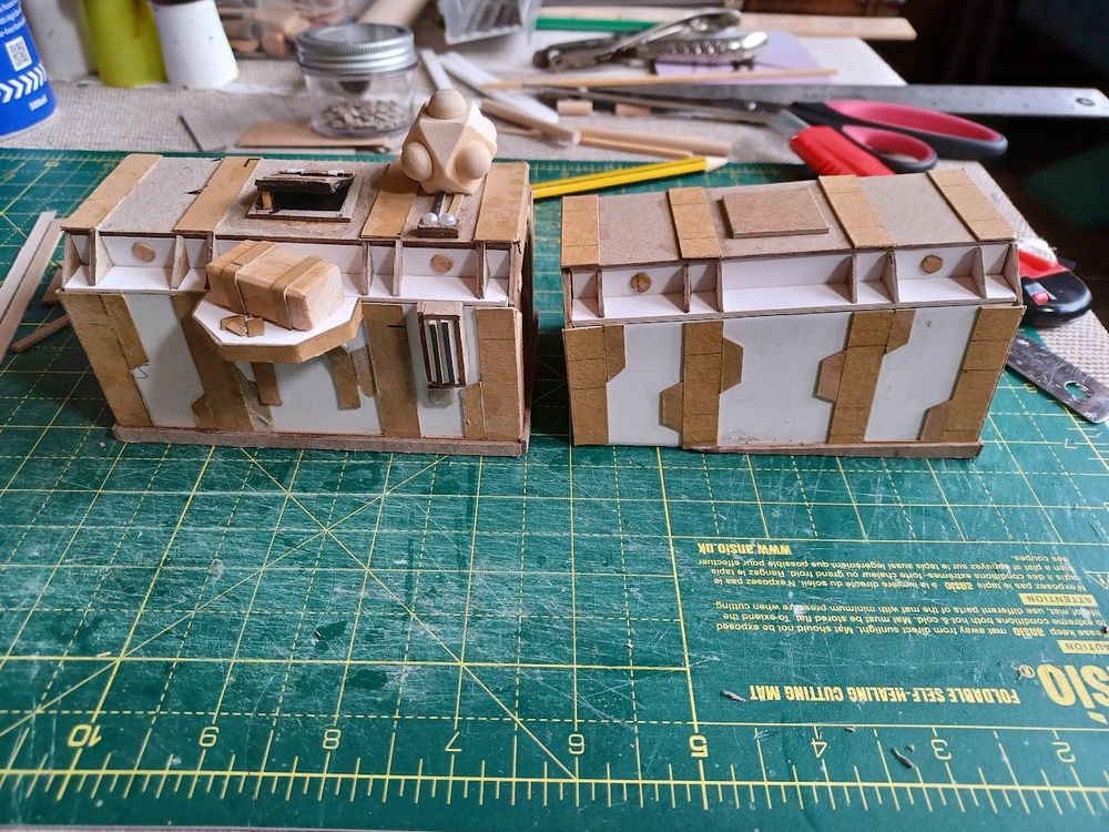 Two cardboard shipping container models, unpainted