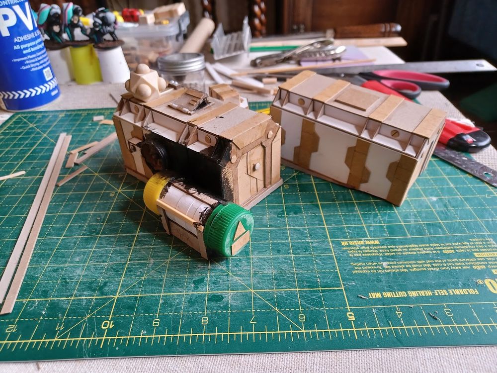Two cardboard shipping container models, unpainted