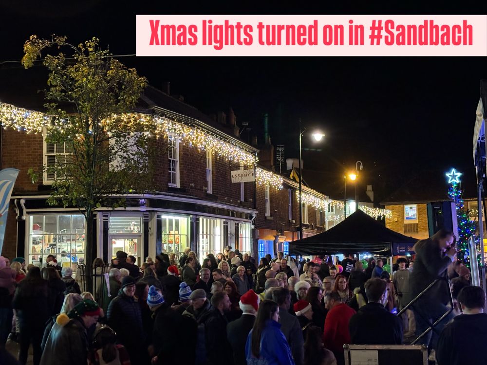 Shop lit up with xmas lights and lots of people looking 