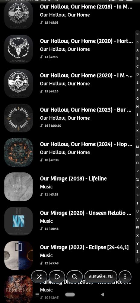 Eine Liste von Musiktiteln in einer App, vermutlich einem Audioplayer. Die Titel sind in weißer Schrift auf schwarzem Hintergrund dargestellt. Jeder Eintrag zeigt ein rundes Albumcover links, gefolgt vom Titel des Albums und darunter dem Namen des Albums oder Künstlers. Die Titel enthalten Jahreszahlen und zusätzliche Informationen in Klammern. Rechts ist eine vertikale Buchstabenleiste zur Navigation sichtbar. Am unteren Bildschirmrand befinden sich Symbole für verschiedene Funktionen, darunter ein Auswahlknopf mit der Beschriftung 'AUSWÄHLEN'.