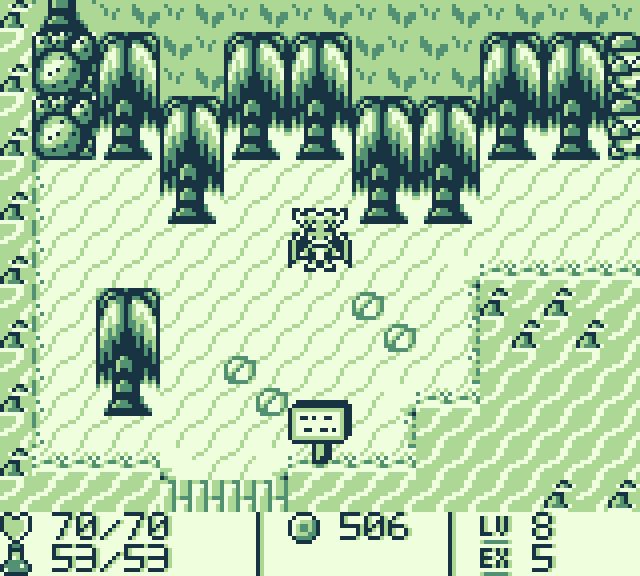 A screenshot of a Game Boy RPG. The player, whom of which is a humanoid dragon, is standing in a tropical looking environment. They are surrounded by palm trees, sand and some cacti.