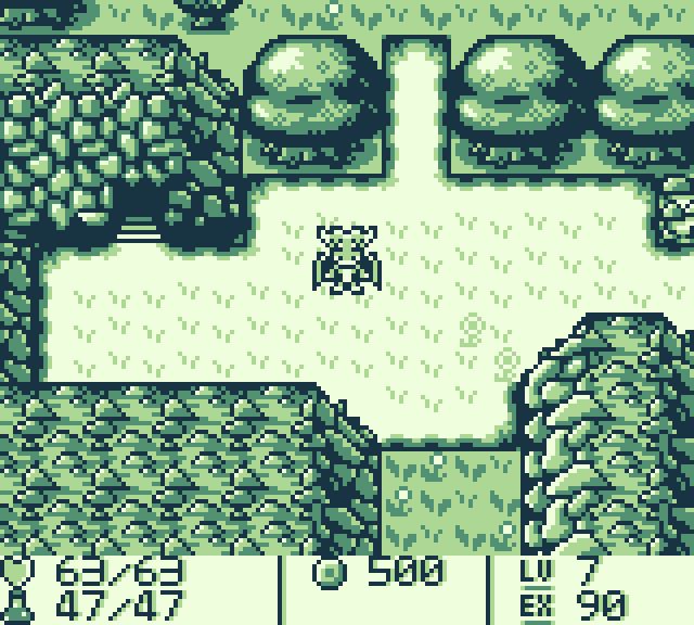 A screenshot of a Game Boy RPG. The player character is in a grassy field. A forested area is behind them and a cave entrance is to their side.