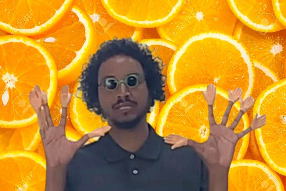 Samba Schutte wearing sunglasses and a tiny plastic hand on each finger. The background is oranges