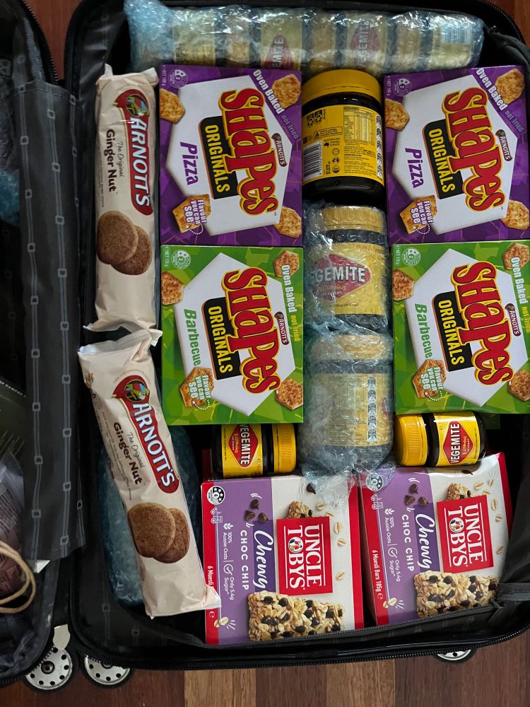 The bottom level has Arnott’s Shapes (Pizza and Barbecue), several jars of Vegemite, Arnott’s Ginger Nut biscuits, and Uncle Tobys Choc Chip muesli bars.