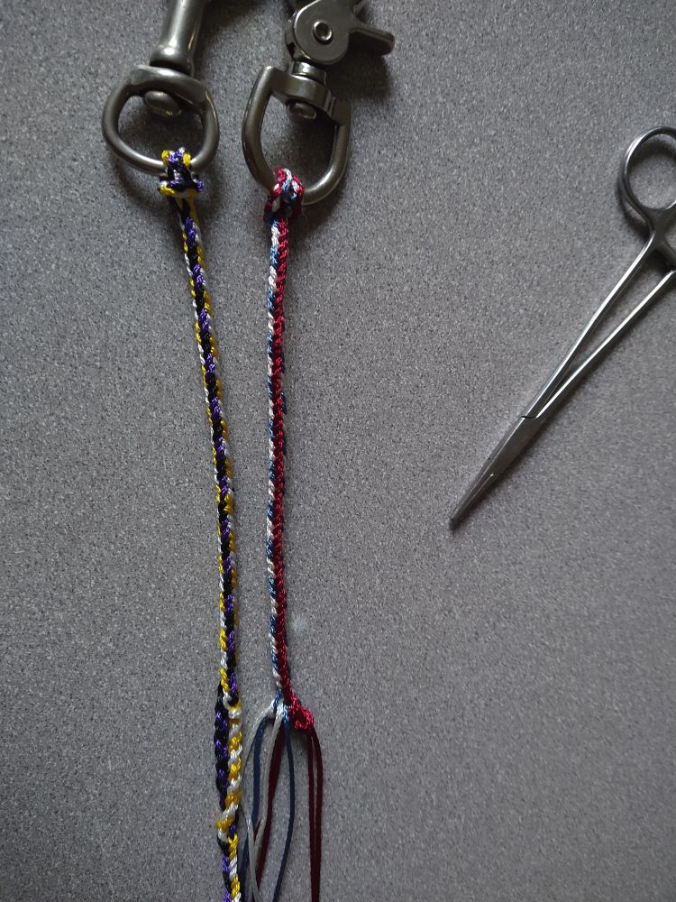 8 strand braided glove clips for Raptor handing, made out of paracord in the colors black, purple, yellow, white and red white, blue. 