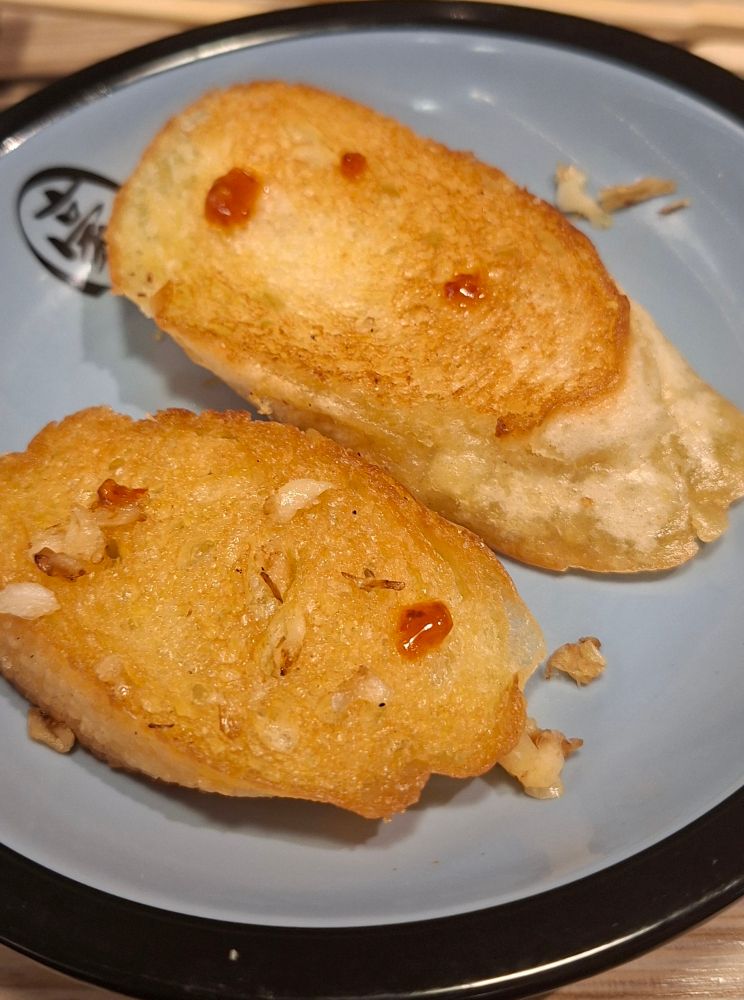 Zwei Stücke Knoblauchbaguette mit je zwei kleinen Kleckserl Sechuan Chiliöl