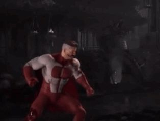 a man in a red superhero costume is standing in the dark .